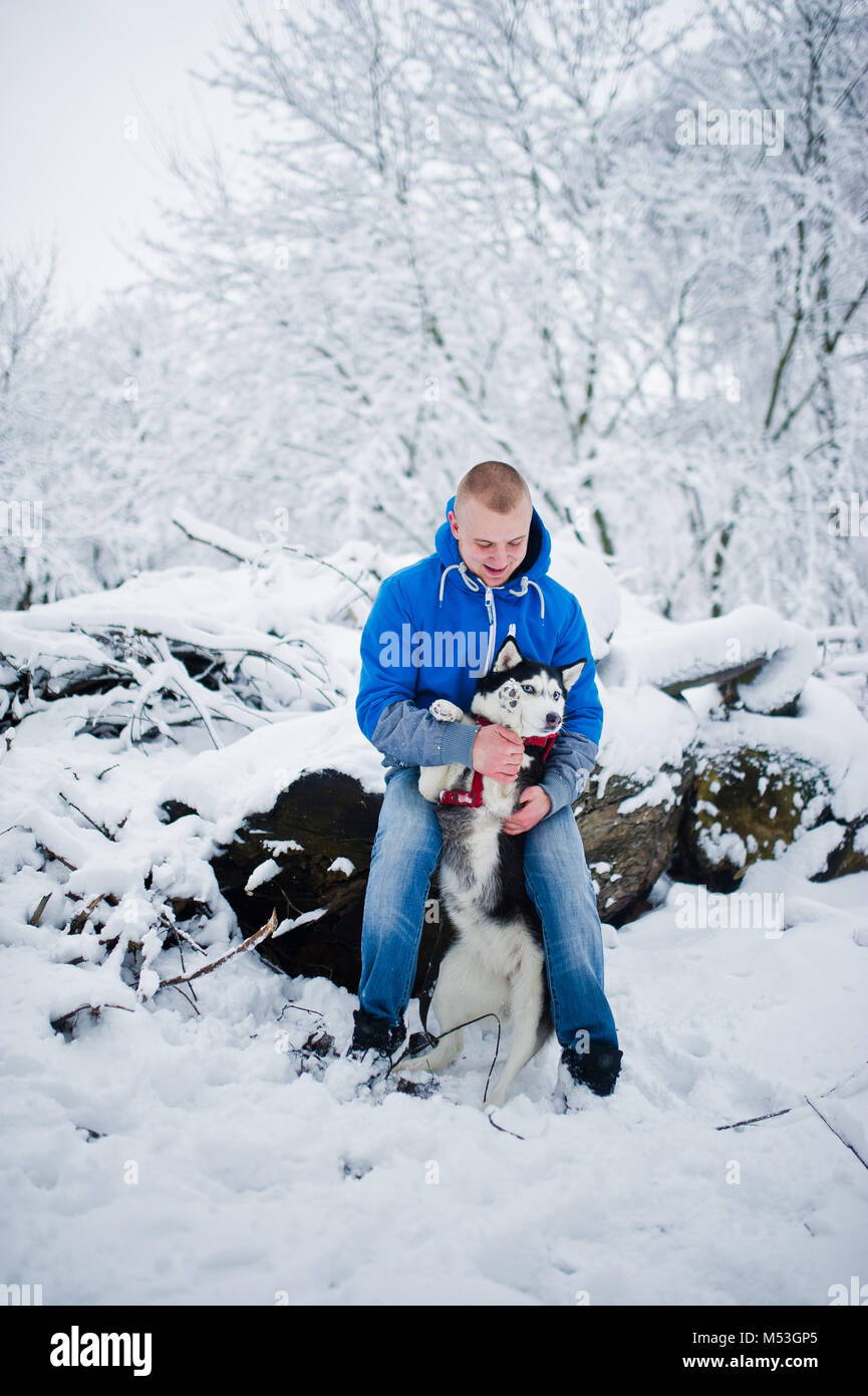 Homme avec chien husky au parc enneigé en hiver. Banque D'Images Homme avec chien husky au parc enneigé en hiver. Banque D'Images