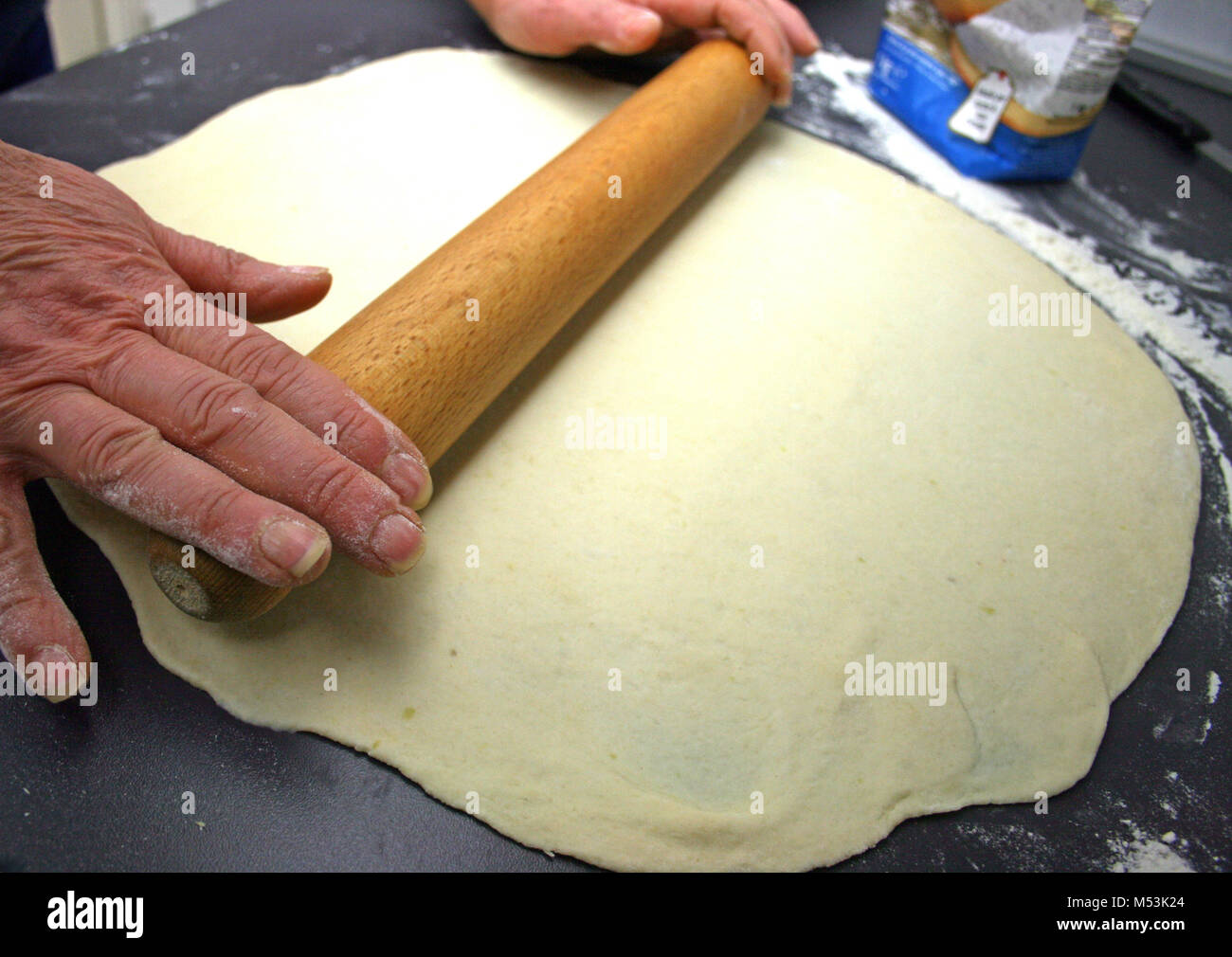 Mains Roulez la pâte sur la table avec un rouleau broche en bois Banque D'Images