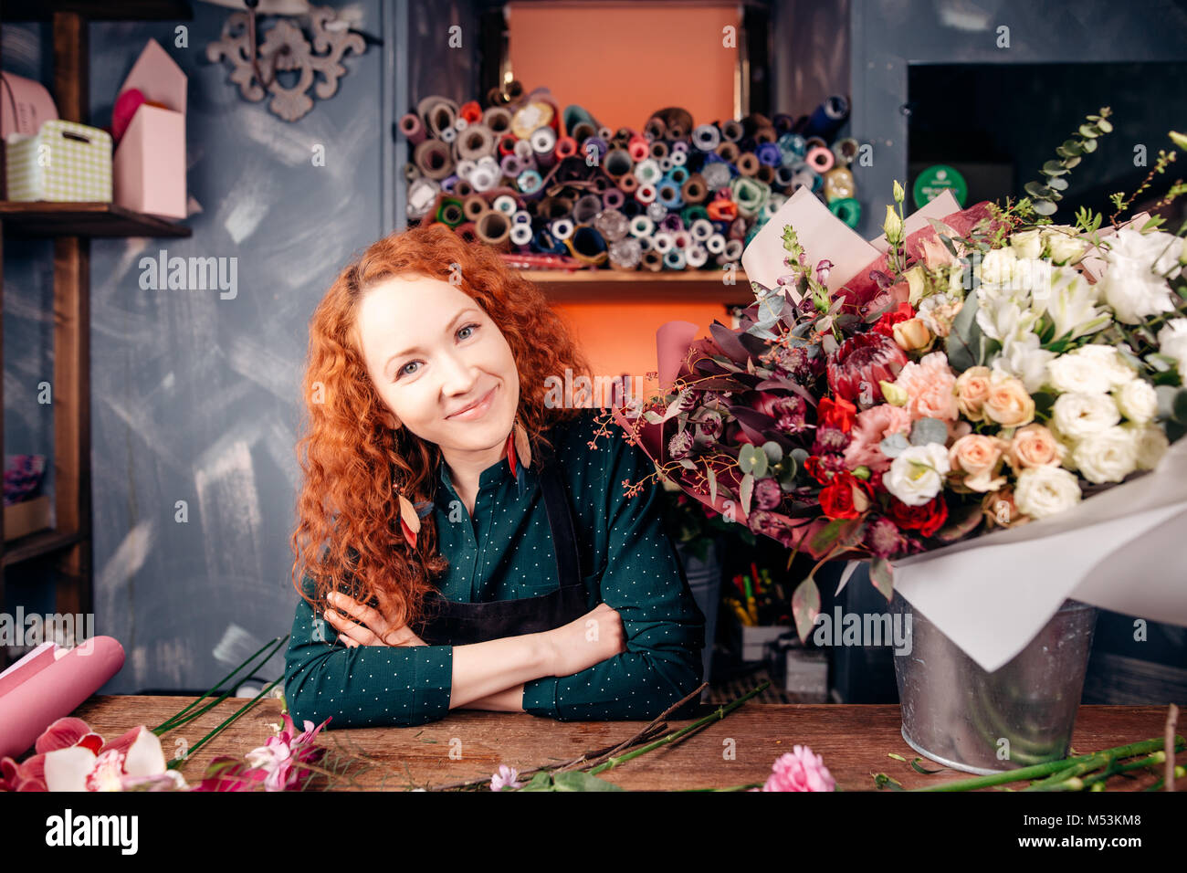Fleuriste designer avec les cheveux rouges et les yeux verts qui travaillent à l'atelier du fleuriste Banque D'Images