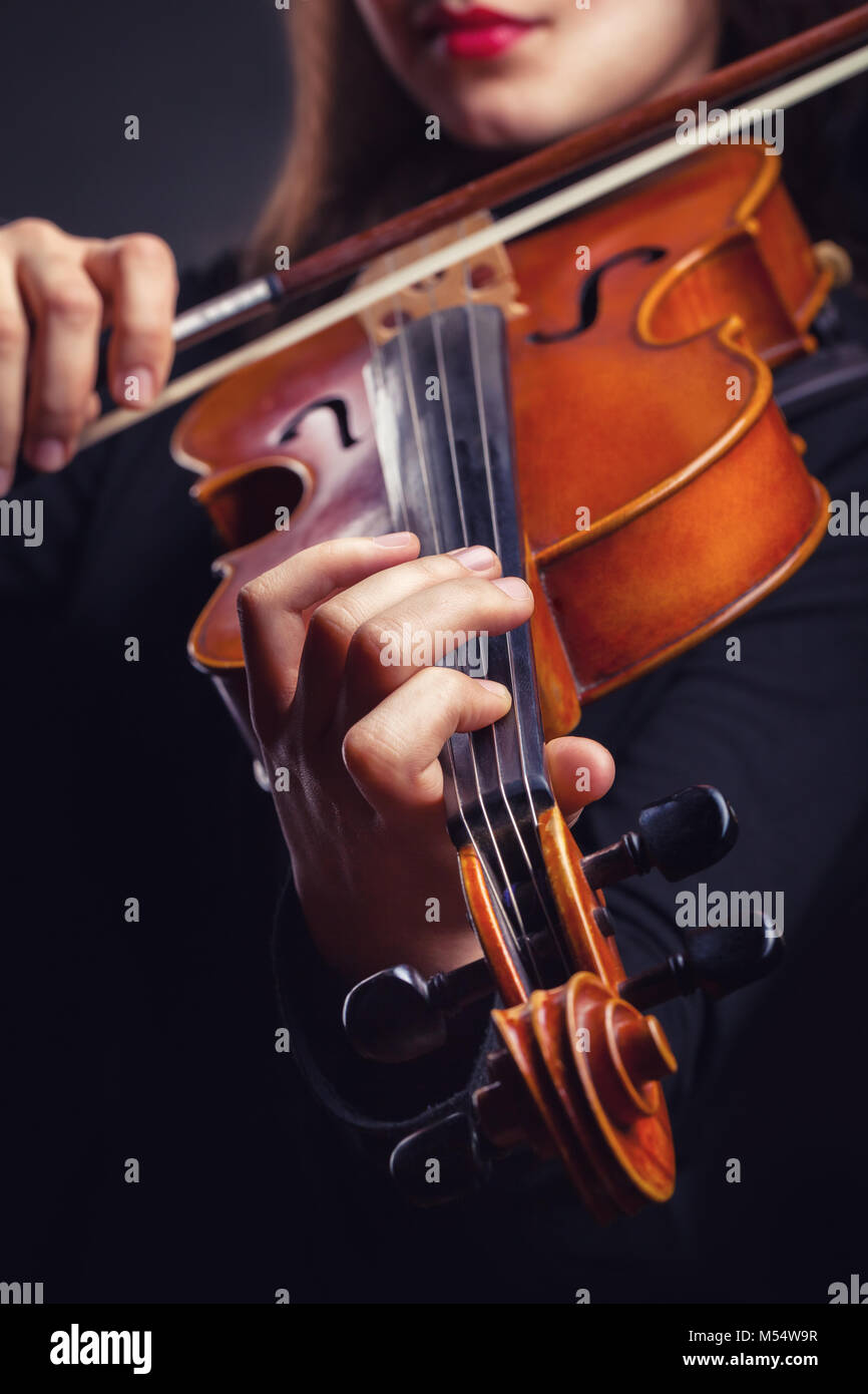 Belle Jeune femme jouant du violon sur fond sombre Banque D'Images