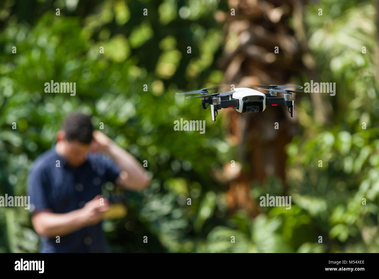 Un drone aérien Mavic DJI en vol avec un homme à la recherche de vol confus à l'arrière-plan Banque D'Images