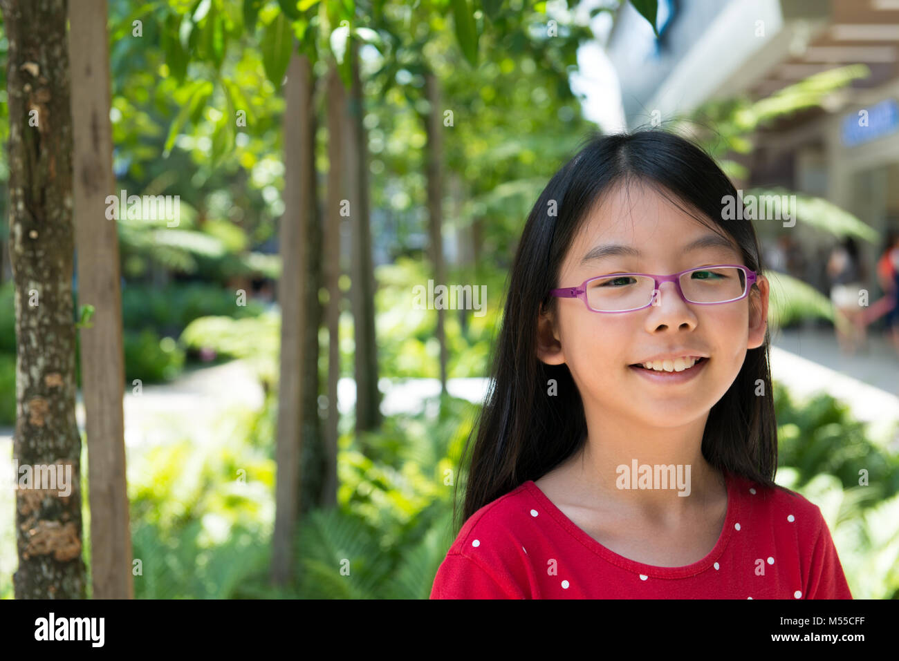 Cute Asian Chinese girl avec lunettes dans park Banque D'Images