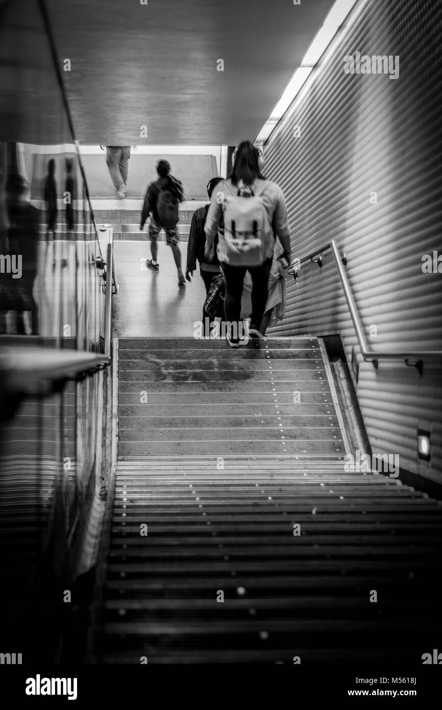 Vue en noir et blanc de jeunes entrant sur la station de métro grâce à un escalier Banque D'Images