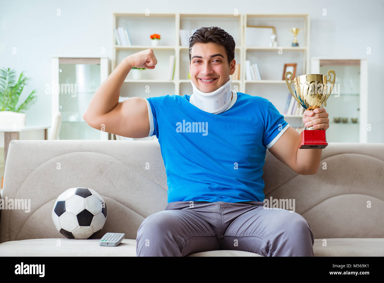 Homme avec blessure au cou à regarder à la maison football soccer Banque D'Images