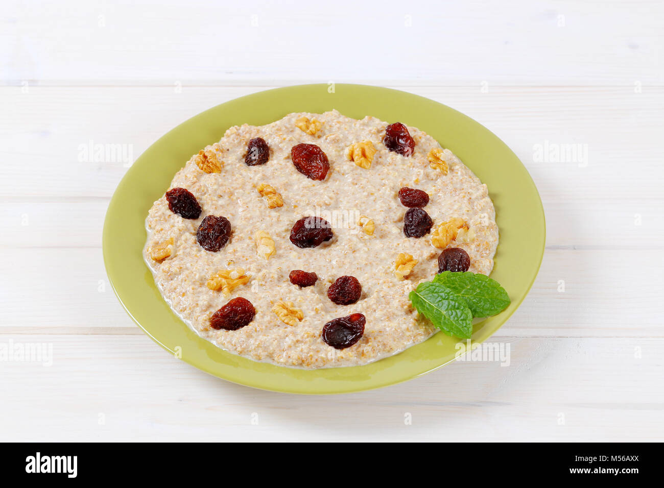 Assiette de porridge d'avoine et aux raisins secs et noix sur fond blanc Banque D'Images