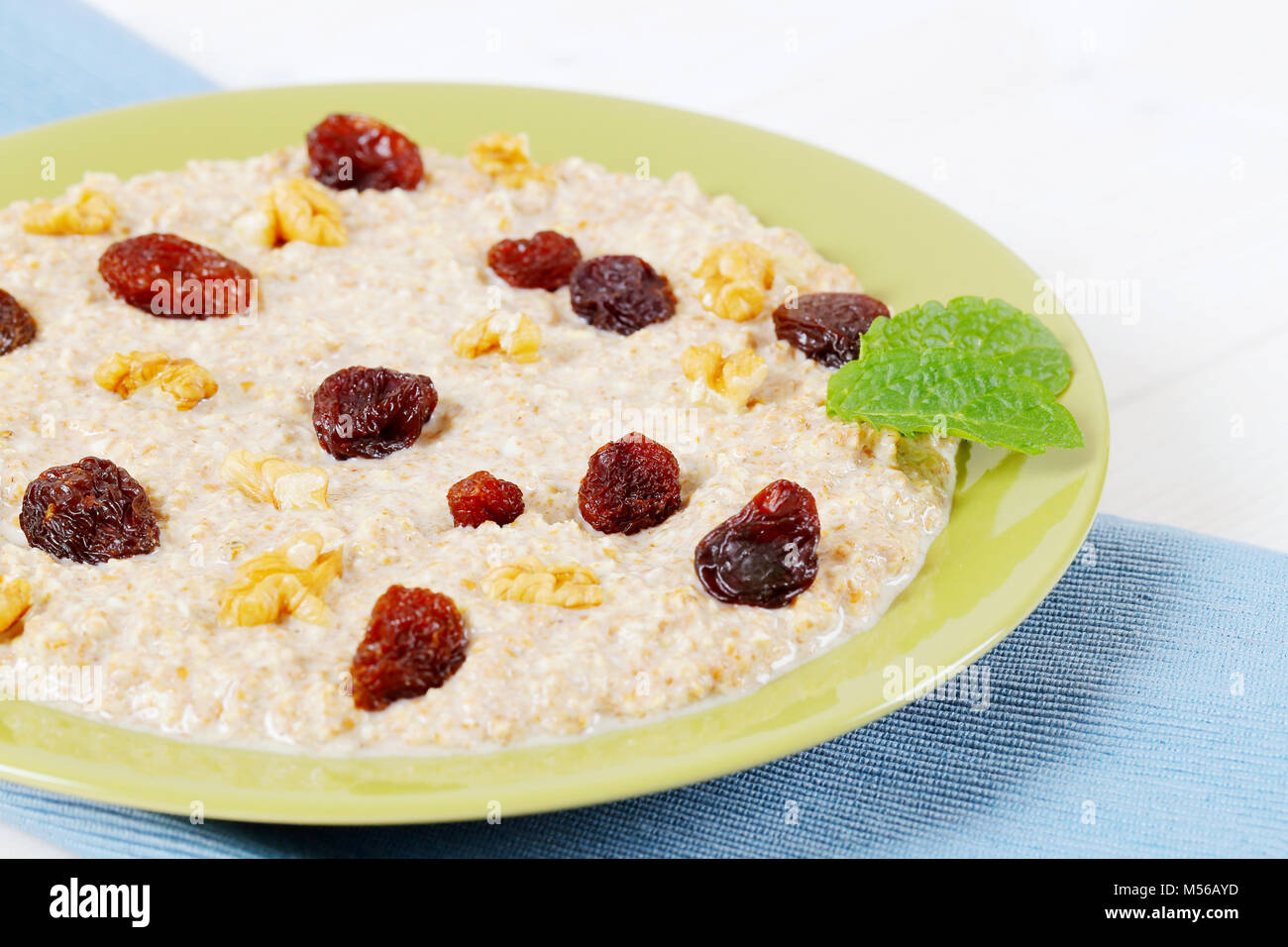 Assiette de porridge d'avoine et aux raisins secs et noix sur place bleu mat - close up Banque D'Images