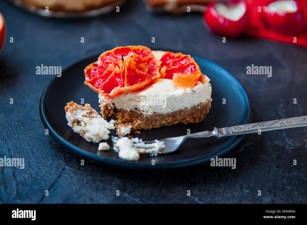 Plaque avec morceau de gâteau au fromage cuit au four avec des tranches de  pamplemousse rouge vintage et fourchette sur le fond de la pierre noire  avec des ingrédients. Focus sélectif, de