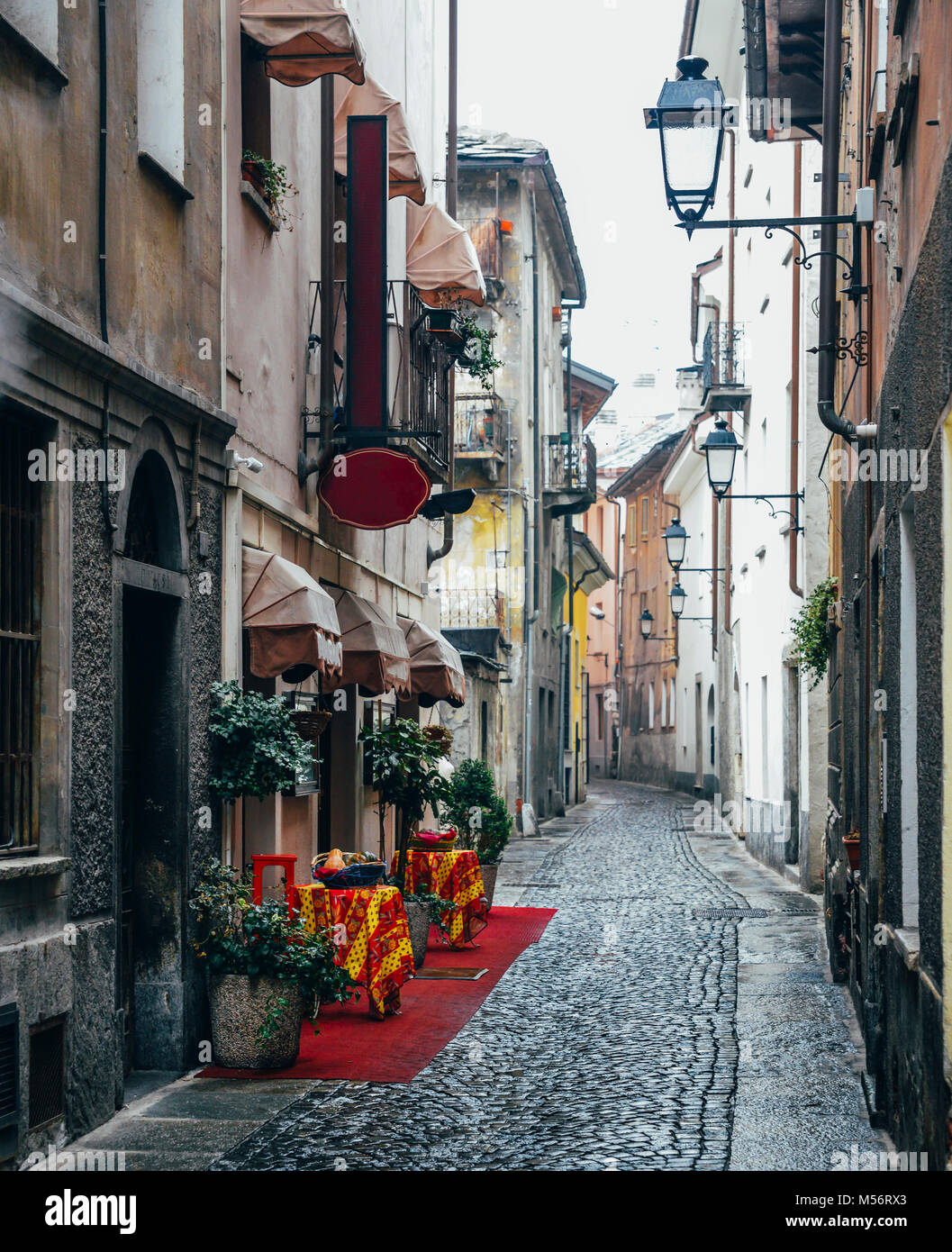 Ruelle pavée pittoresque à Aoste, Italie avec des tapis rouge entrée de restaurant italien sur la gauche Banque D'Images