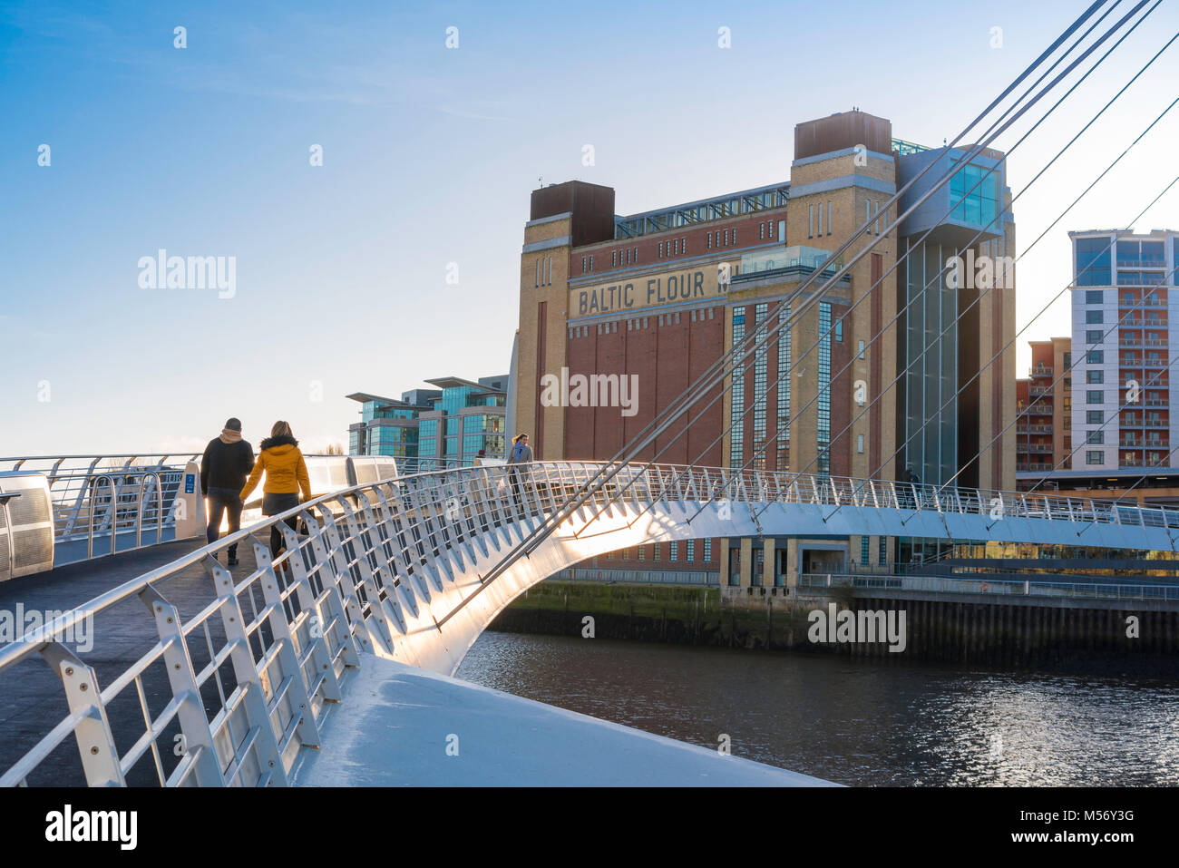 Newcastle Upon Tyne, un jeune couple à pied à travers le Millennium Bridge vers le Baltic Centre for Contemporary Art à Gateshead, Angleterre bâtiment,UK Banque D'Images