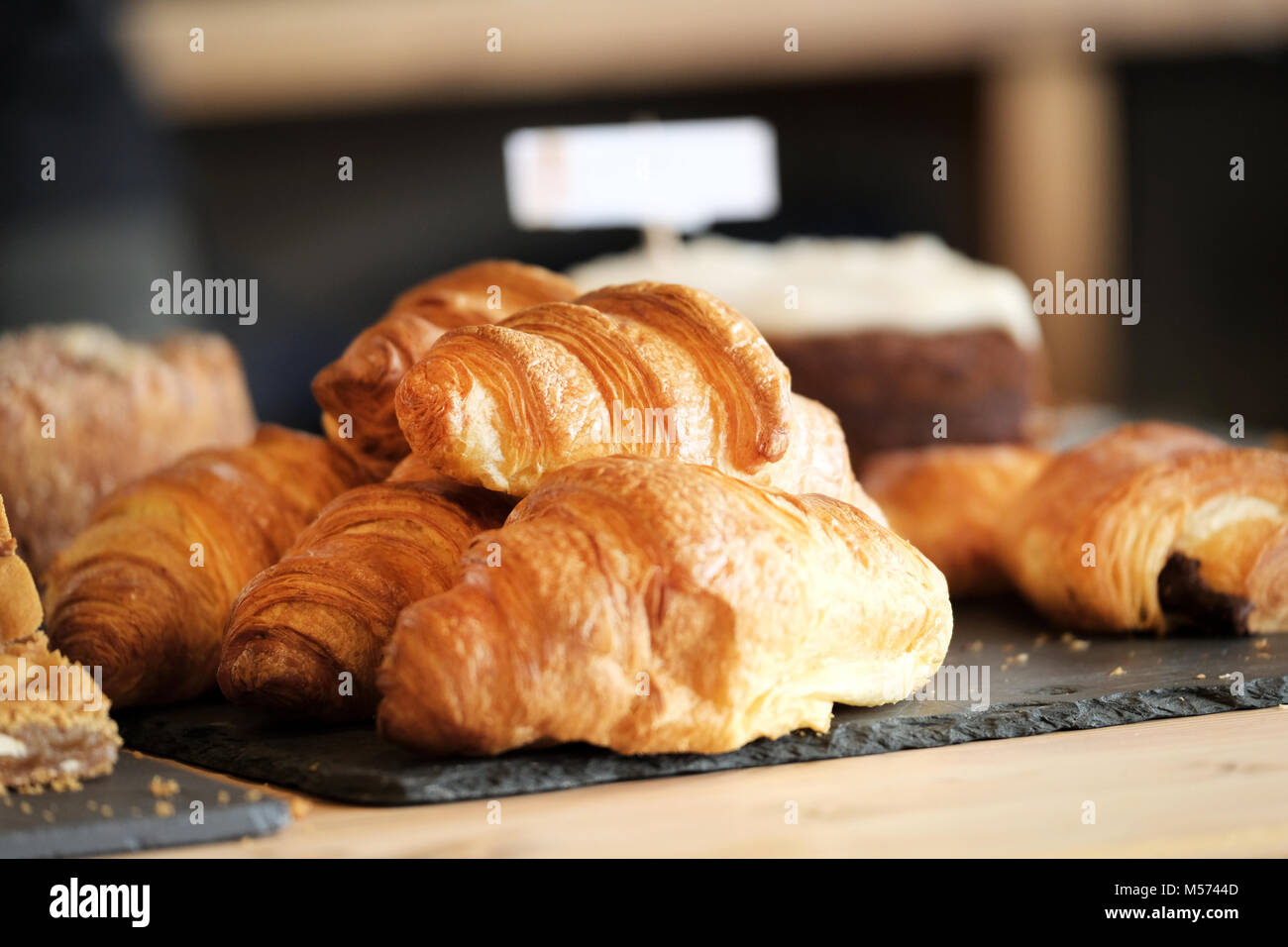 Des petits, d'or, tous les beurre, croissants à la vente affiché sur une ardoise comptoir dans un café épicerie fine à Poole, UK Banque D'Images