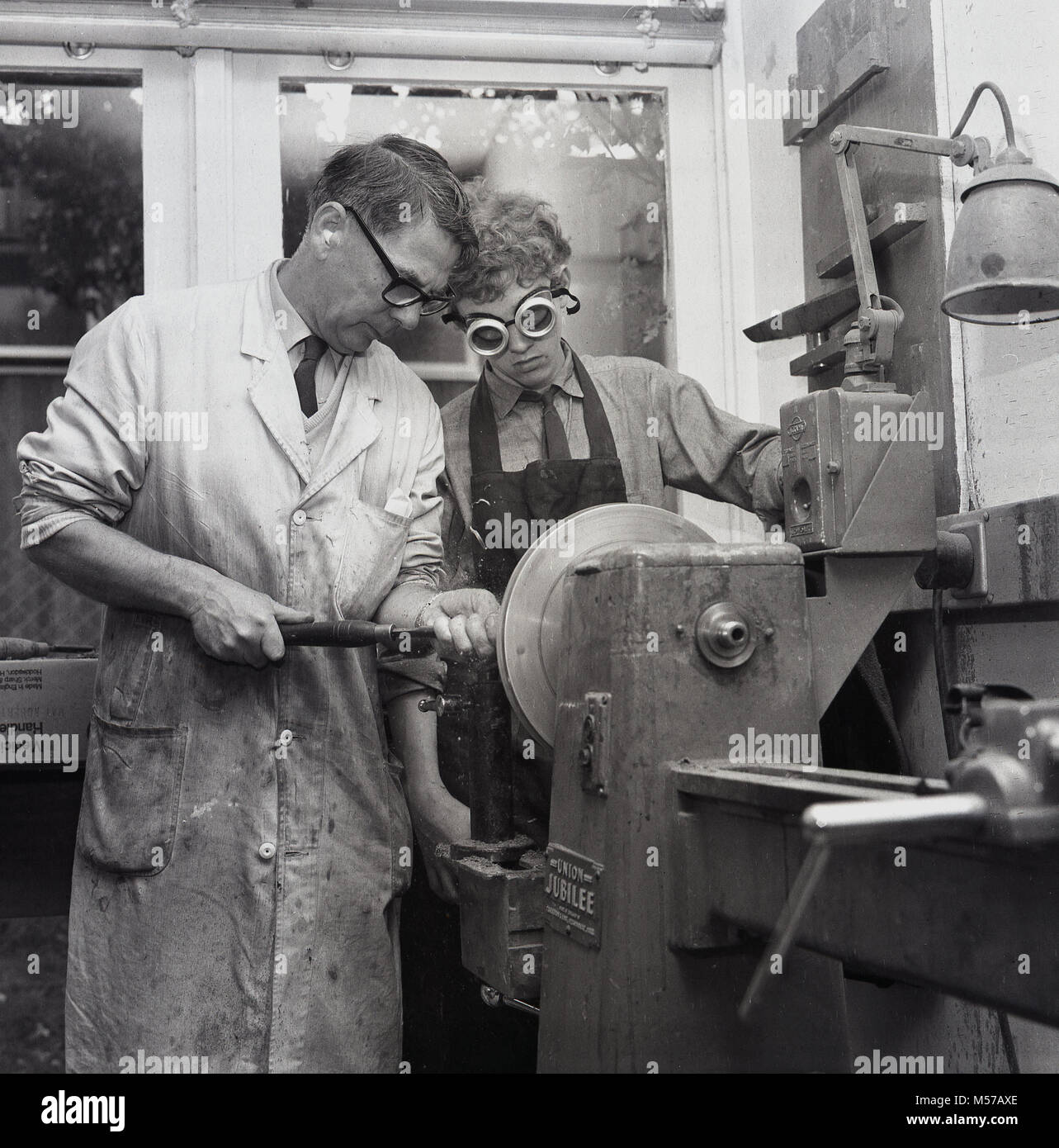 1968, historique, dans le sud de Londres, en Angleterre, les jeunes adolescents à une pension dans l'état d'un atelier avec un professeur à l'aide d'une latte de métal au cours d'une classe. Banque D'Images