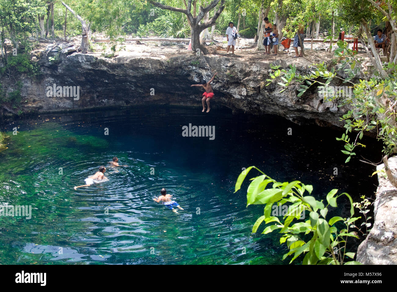 Garçon saute dans l'eau limpide de Cenote El Eden, Cenotes, Tulum, Riviera Maya, Quintana Roo, Yucatan, Mexique, Caraïbes Banque D'Images