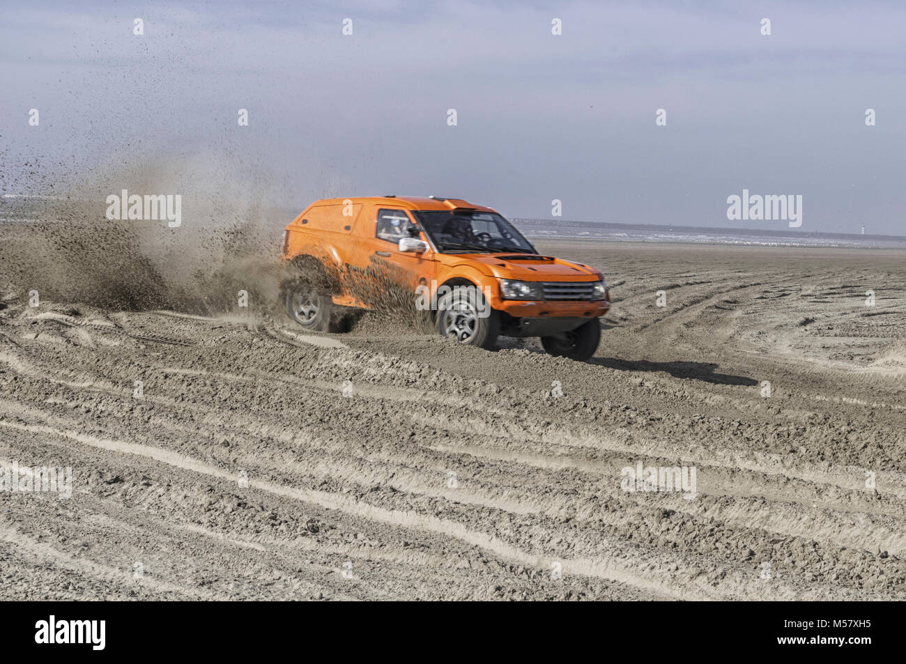 Voiture de course orange sur la plage à pleine vitesse Banque D'Images