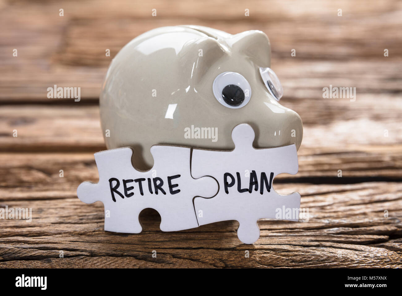 Gros plan du plan de retraite reliés par des pièces de puzzle tirelire sur bois Banque D'Images