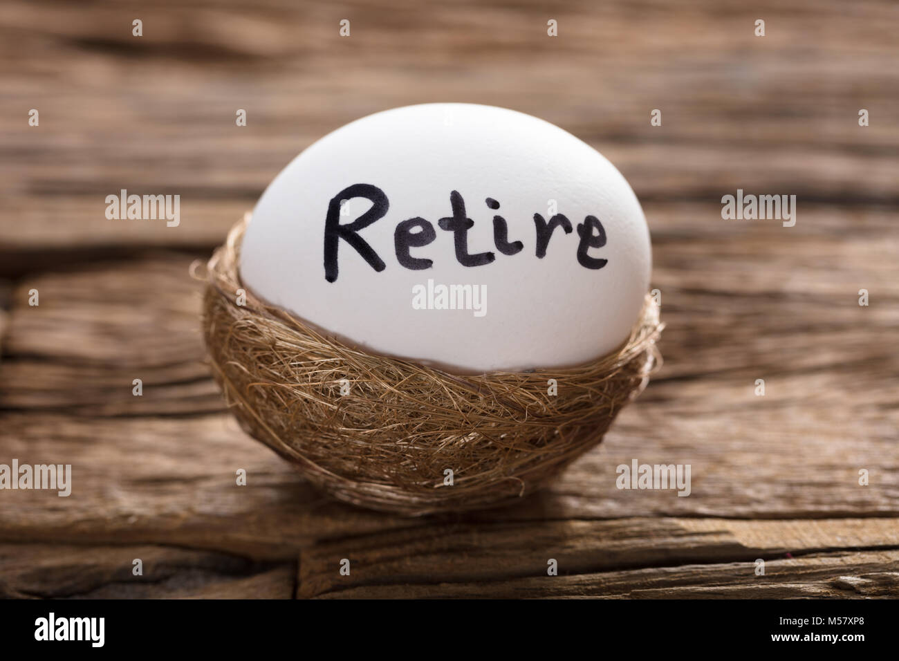 Libre de prendre leur retraite écrit sur white egg in nest sur bois Banque D'Images