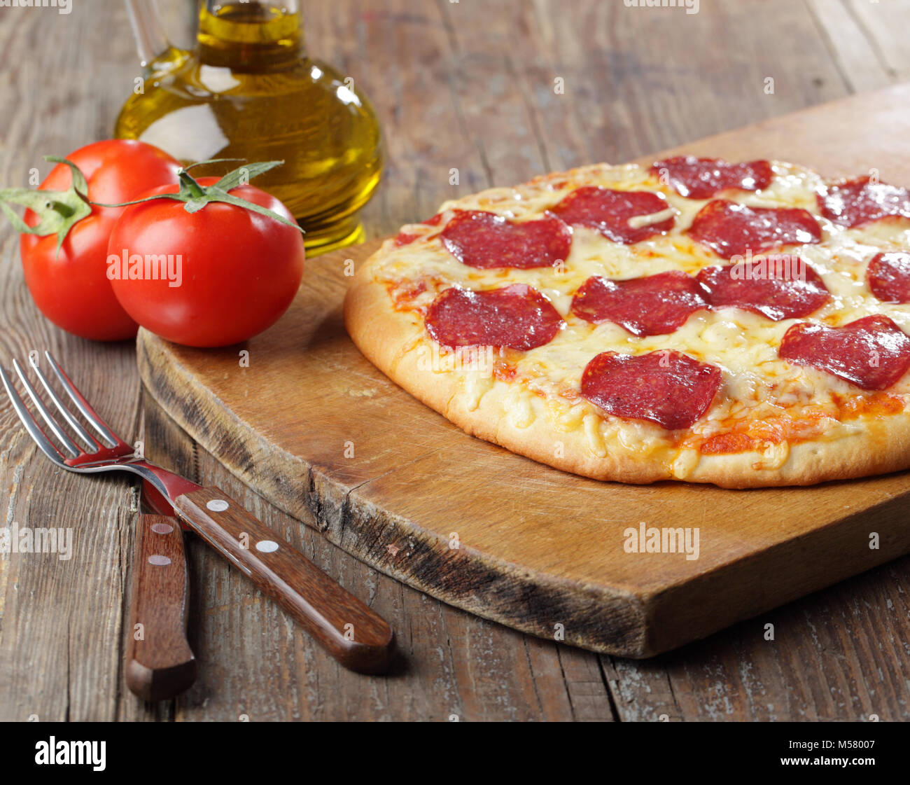 Pizza au salami et fromage sur une planche à découper Banque D'Images
