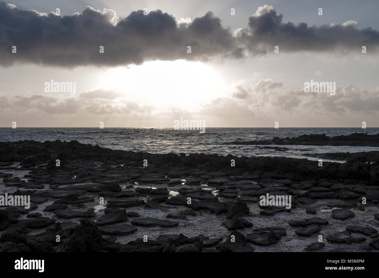 Un champ de lave dans la région de à la plage La Concha à El Cotillo, Fuerteventura, Espagne, Europe, Afrique. Photo prise contre le soleil. Un couds la mer à l'arrière. Banque D'Images