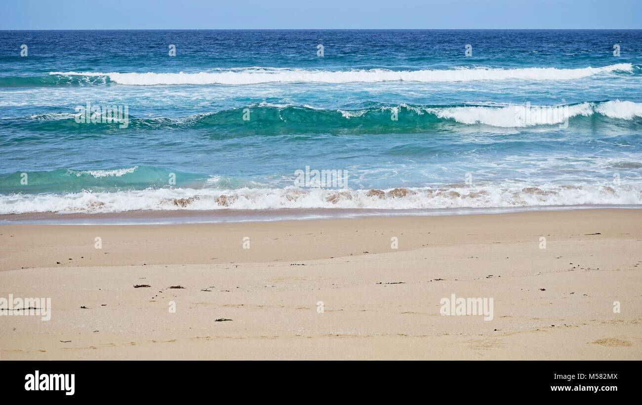 Les petites vagues se brisant sur la plage avec du sable en premier plan. Banque D'Images
