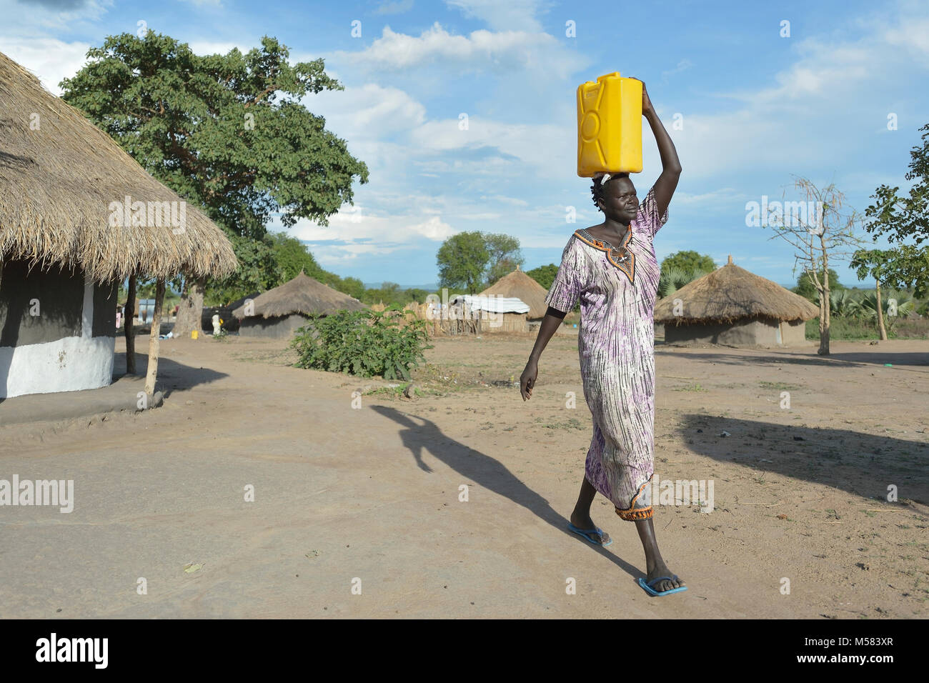 Une femme dinka du Soudan du Sud transporte l'eau dans le camp de réfugiés de rhinocéros dans le nord de l'Ouganda. Banque D'Images
