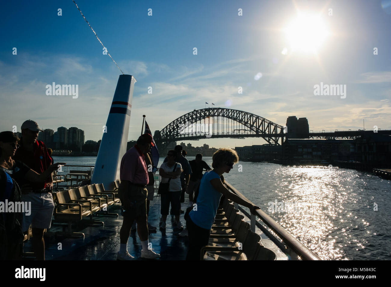 Les personnes à la recherche à la Sydney Harbour Bridge à partir d'un bateau au coucher du soleil Banque D'Images