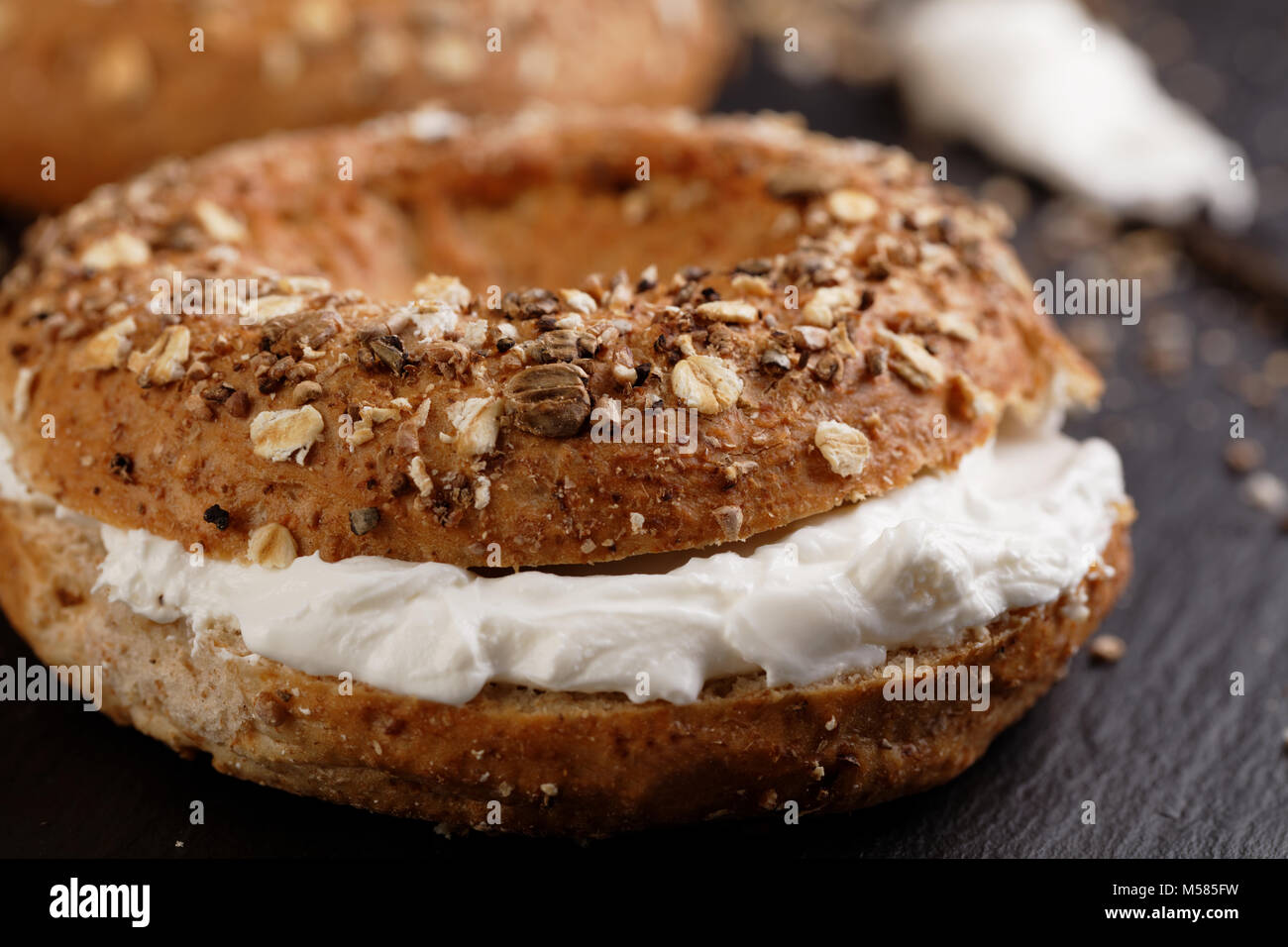 Sandwich Bagel avec fromage doux sur une planche à découper ardoise Banque D'Images