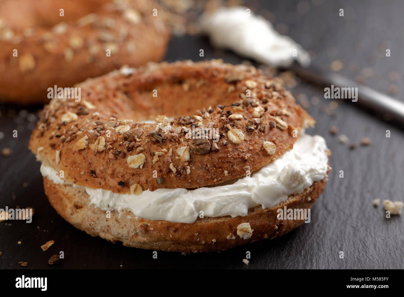 Sandwich Bagel avec fromage doux sur une planche à découper ardoise Banque D'Images