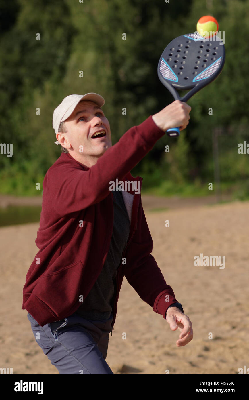 Homme mûr la pratique du beach tennis sur la plage Banque D'Images