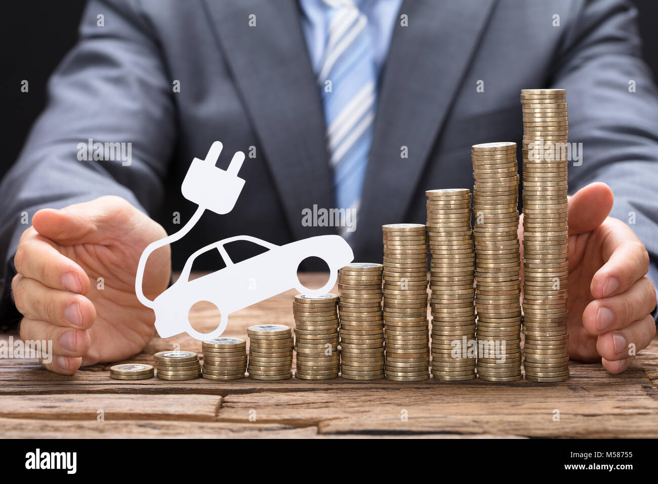 Portrait of businessman la protection des pièces de voiture électrique à table en bois Banque D'Images