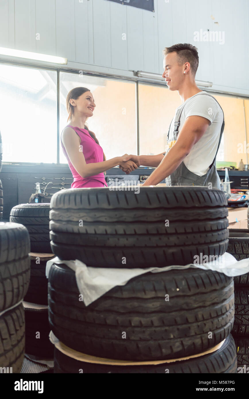 Belle auto mechanic aide une clientèle féminine de choisir entre différents pneus de haute qualité dans un atelier de réparation automobile contemporaine Banque D'Images