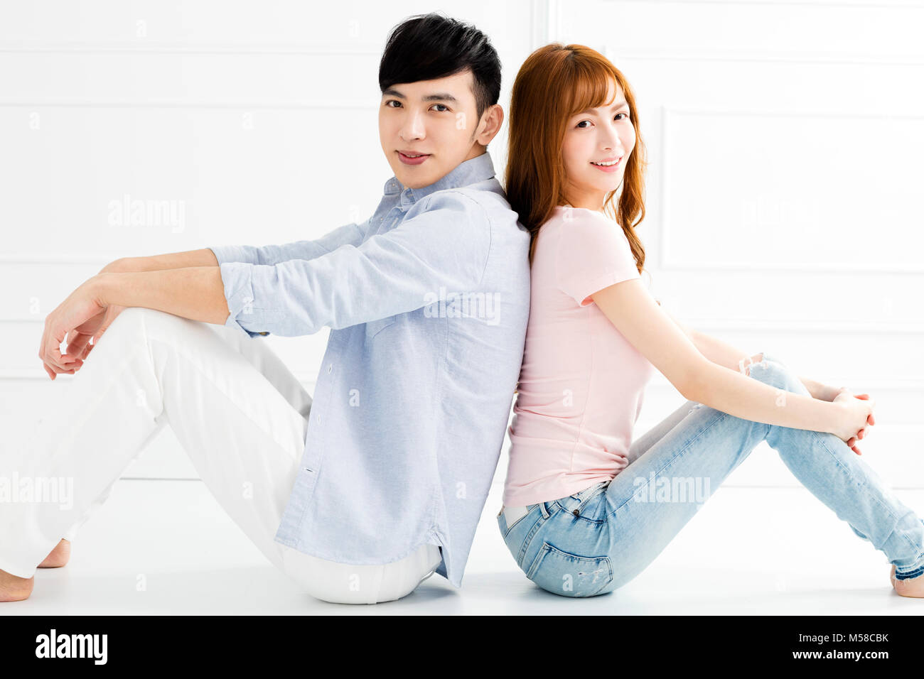 Jeune couple assis ensemble sur le plancher Banque D'Images