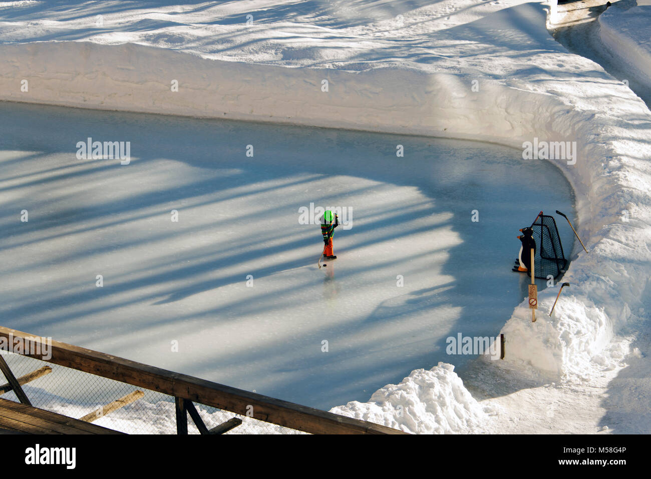 Un enfant jouer au hockey sur glace dans les Alpes suisse en hiver Banque D'Images