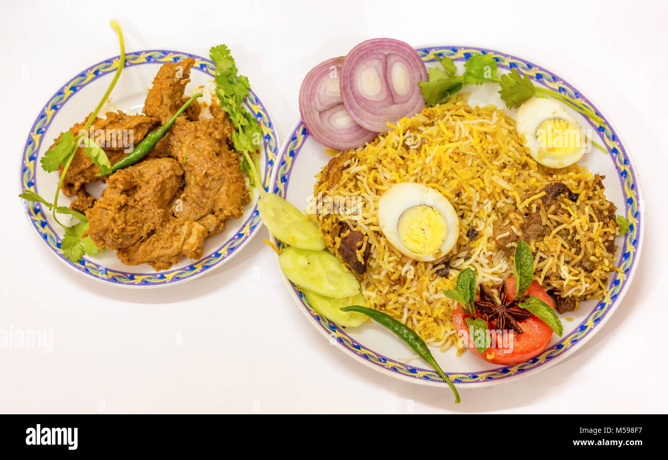 La cuisine Mughlai indienne de poulet biriyani épicé (riz) et mutton kosha (curry) avec la salade et les rondelles d'oeuf. Banque D'Images