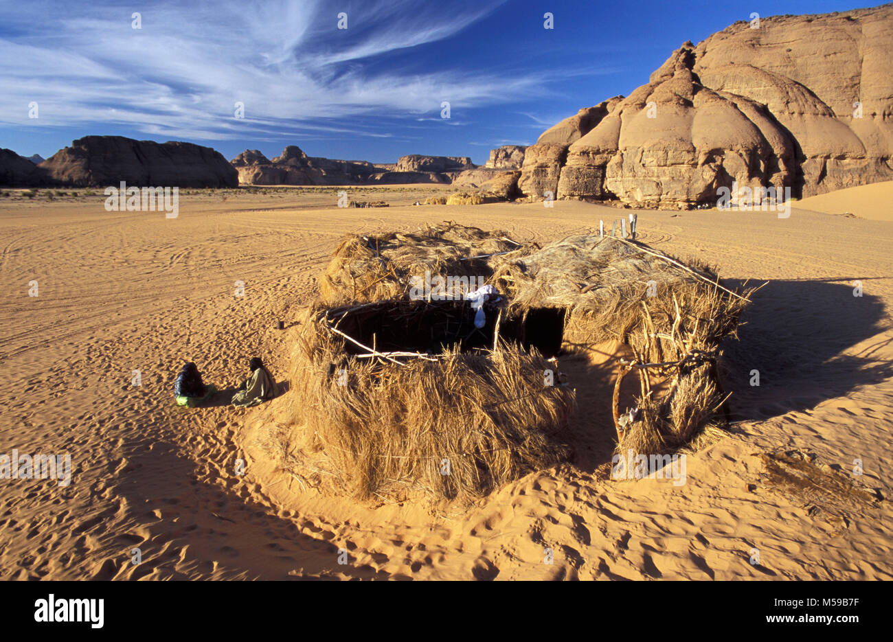 La Libye. Près de Ghat. Désert du Sahara. Akakus (Acacus) Parc National. L'homme de tribu touareg devant sa maison en paille (zeriba). Banque D'Images