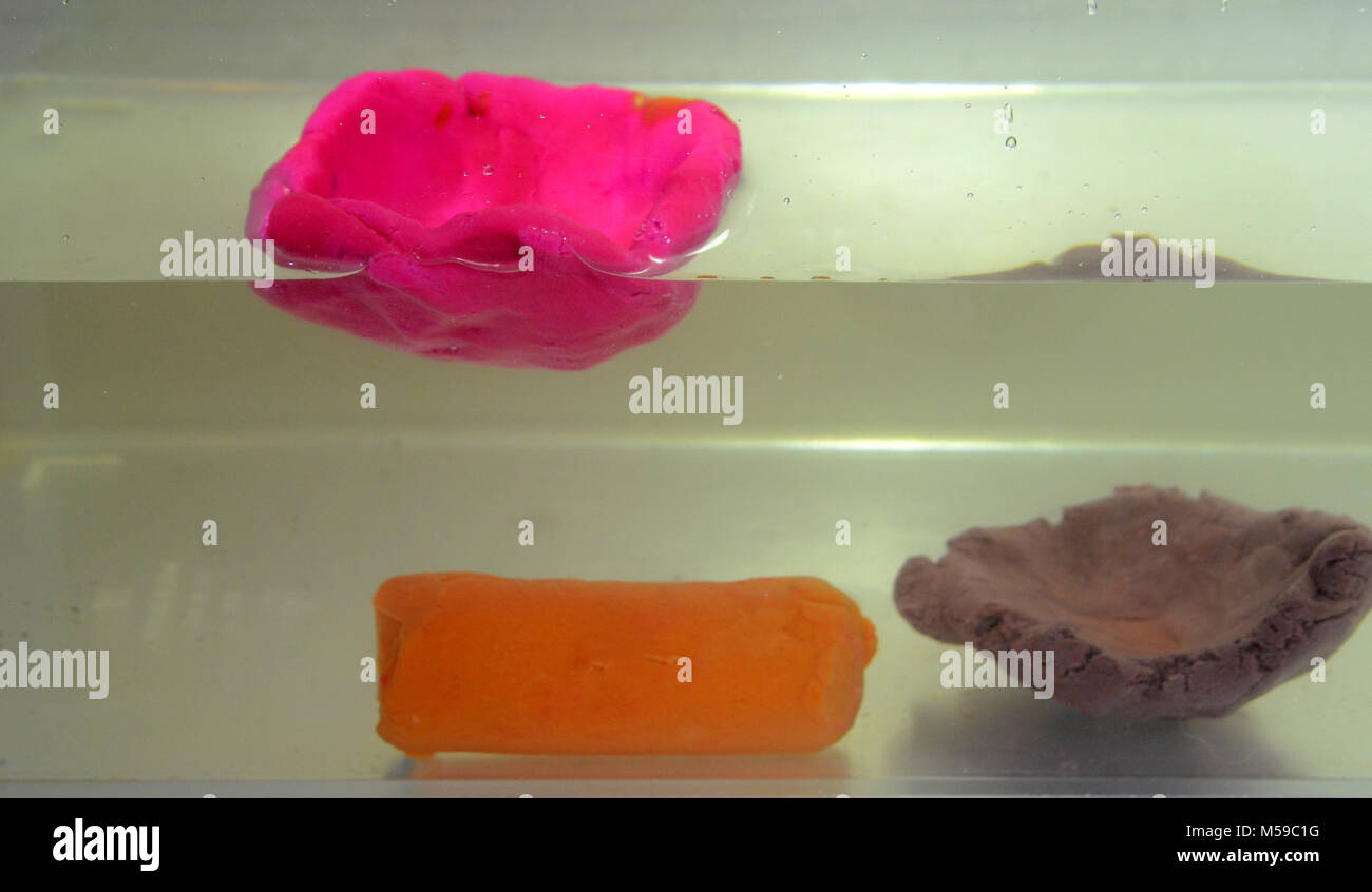 Démonstration de la flottabilité : 3 morceaux de pâte à modeler, deux formé comme une tasse, un cylkinder comme un solide placé dans l'eau. Le cylindre massif vasque, whil Banque D'Images