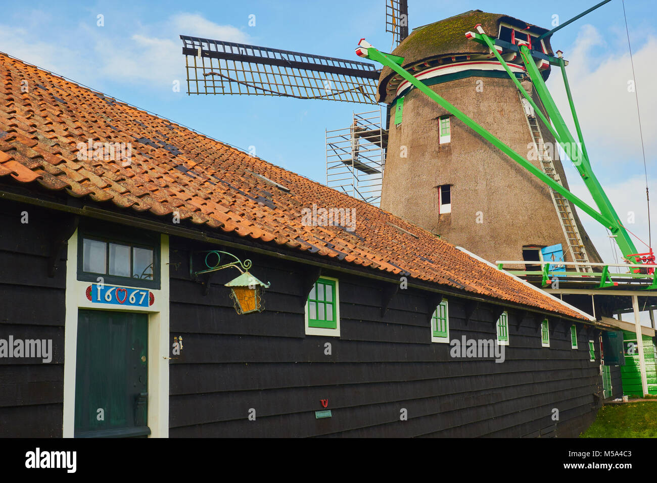 Bâtiment en bois du 17ème siècle et l'homme sur l'échelle de la décoration moulin Zaanse Schans, un village près de Zaandijk municipalité de Zaanstad, Pays-Bas. Banque D'Images