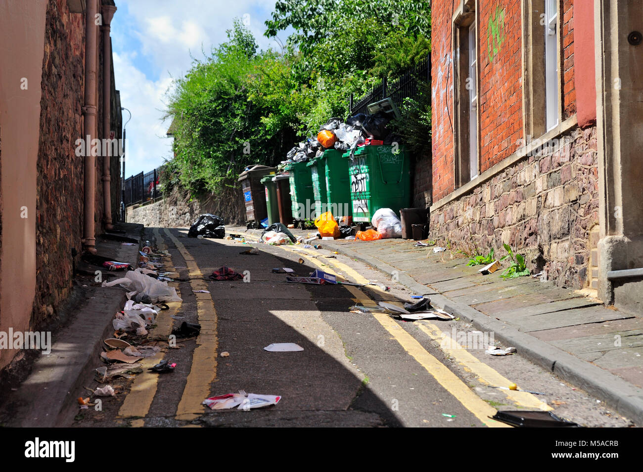 Ordures et déchets ordures petite allée avec des bacs de déchets qui débordent, UK Banque D'Images