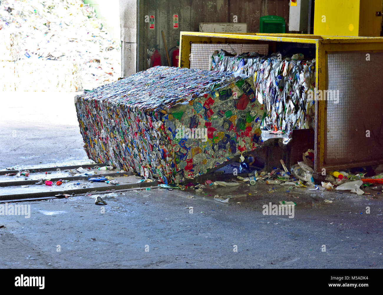 Les boîtes en fer post-consommation écrasé et compactés sous caution au centre de recyclage qu'il quitte le compacteur automatique Banque D'Images