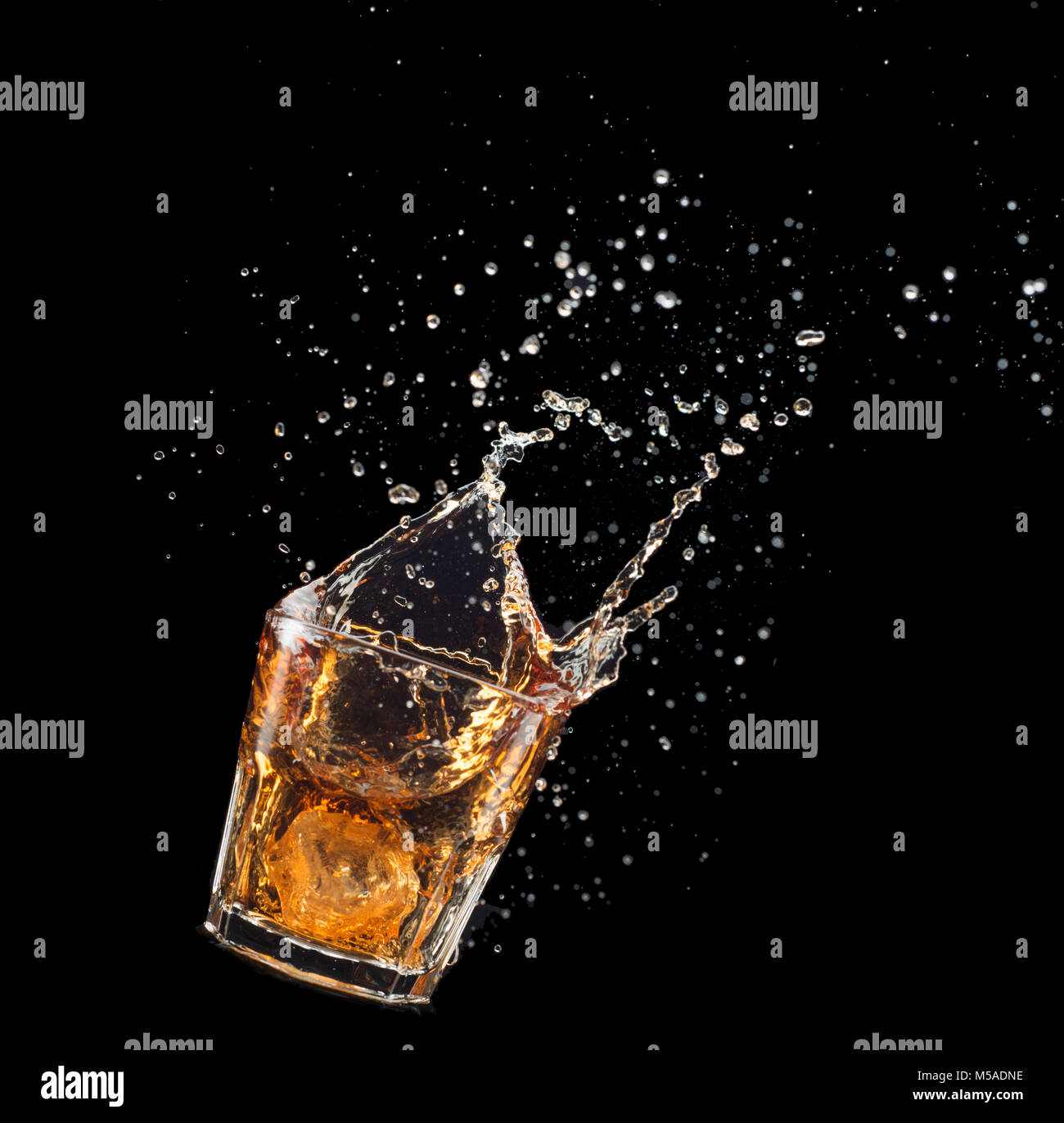 Verre de whisky avec splash isolé sur fond noir. Banque D'Images