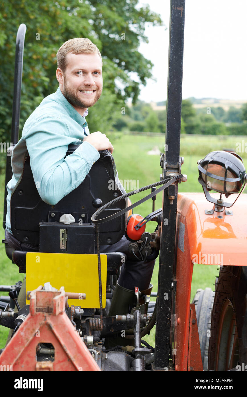 Portrait d'agriculteur assis sur le tracteur dans le champ, Banque D'Images