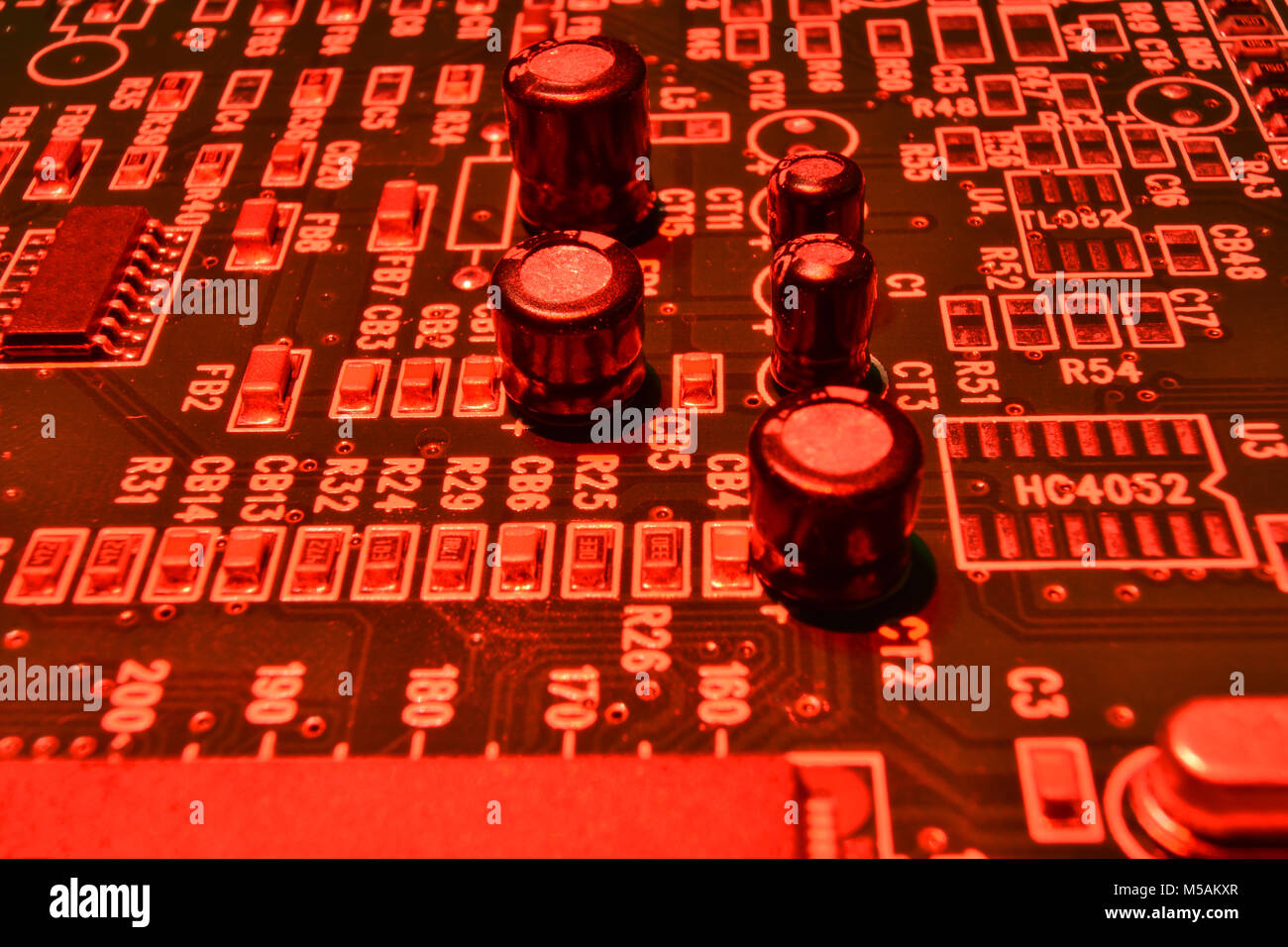 Gros plan d'une carte à circuits imprimés, composants électroniques en lumière rouge Banque D'Images