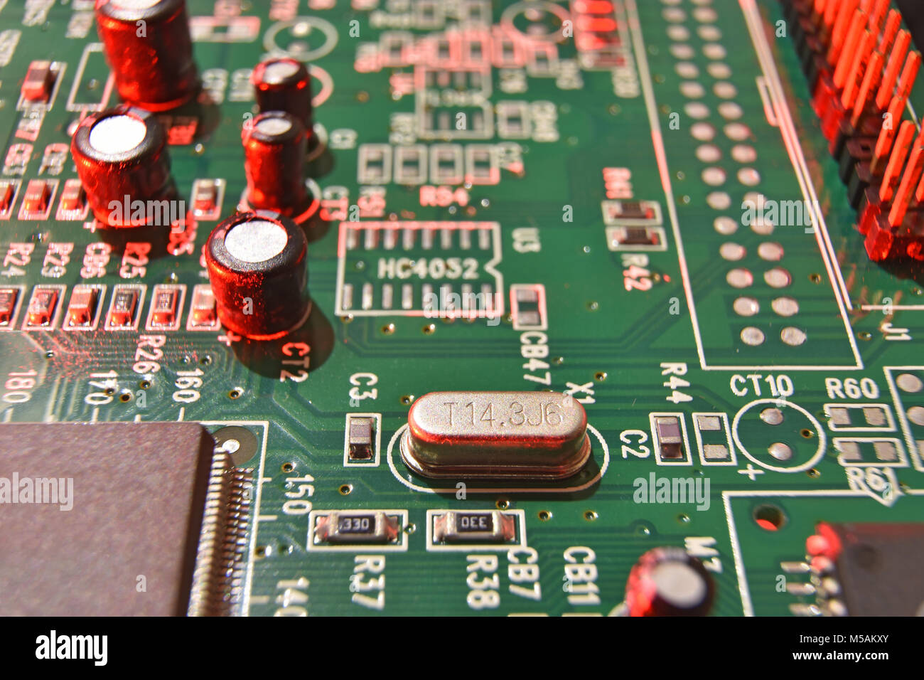 Gros plan d'une carte à circuits imprimés, composants électroniques en lumière rouge Banque D'Images