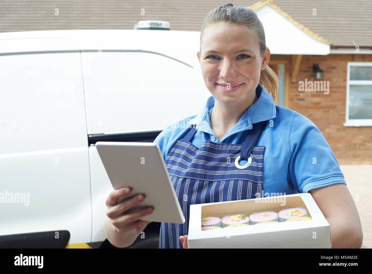 Portrait of Female Baker avec tablette numérique faire la livraison à domicile de Cupcakes Banque D'Images
