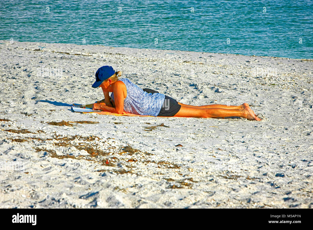 Femme profiter du soleil et lire un livre sur la plage, à la pointe de Port Boca Grande en Floride, USA Banque D'Images