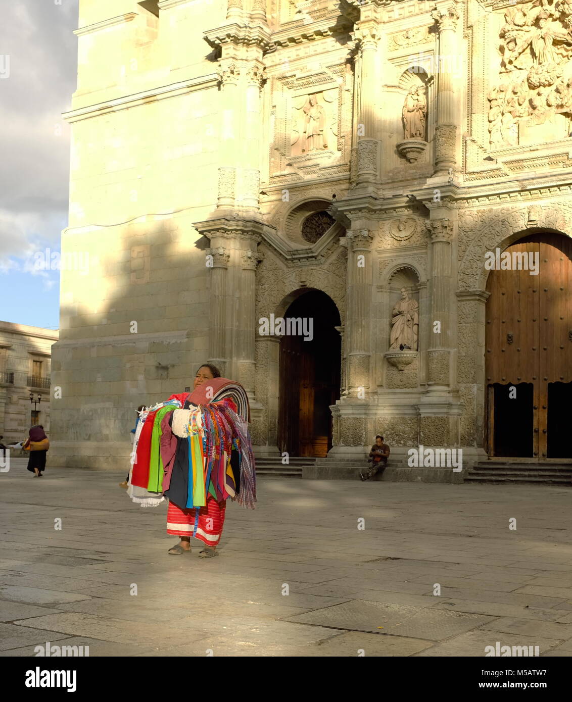 Le soleil se pose majestueusement sur une femme qui se tient stoïquement devant la cathédrale notre-Dame de l'Assomption à Oaxaca, au Mexique. Banque D'Images