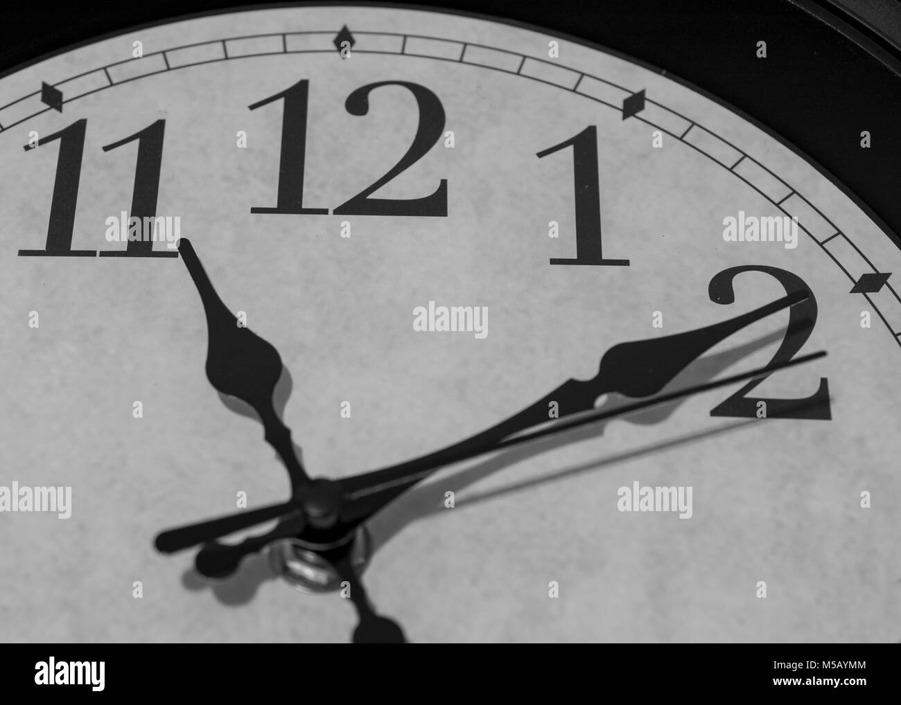 Gros plan sur les pointeurs d'une horloge marquant dix minutes après 11 heures - le rendu noir et blanc Banque D'Images