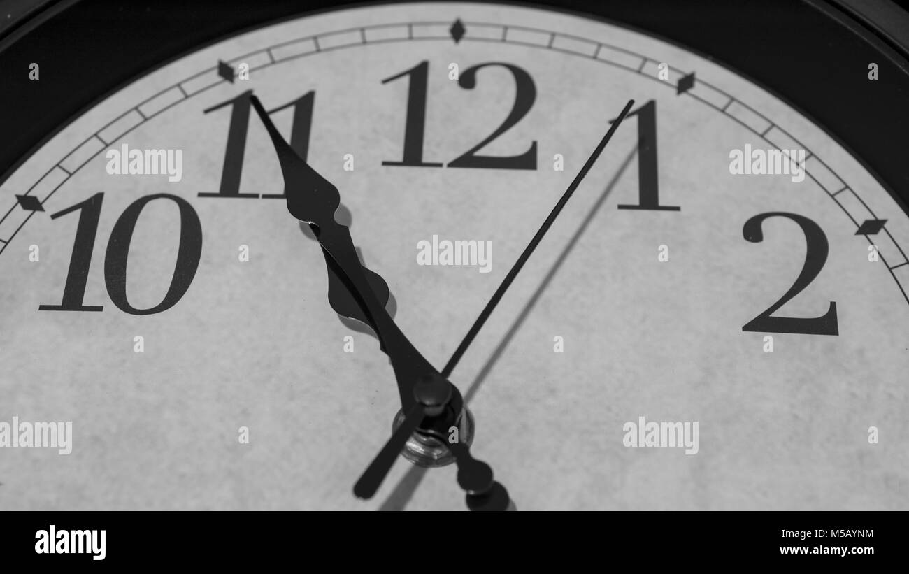 Gros plan sur les pointeurs d'une horloge marquant cinq minutes avant 11 heures - le rendu noir et blanc Banque D'Images