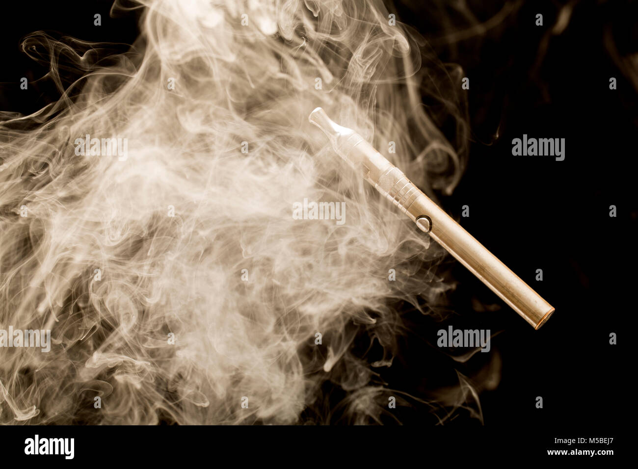 Electric cigarette ou E cigarette entouré par les vapeurs de son e liquide. England UK GB. Photographié sur un fond noir. Banque D'Images