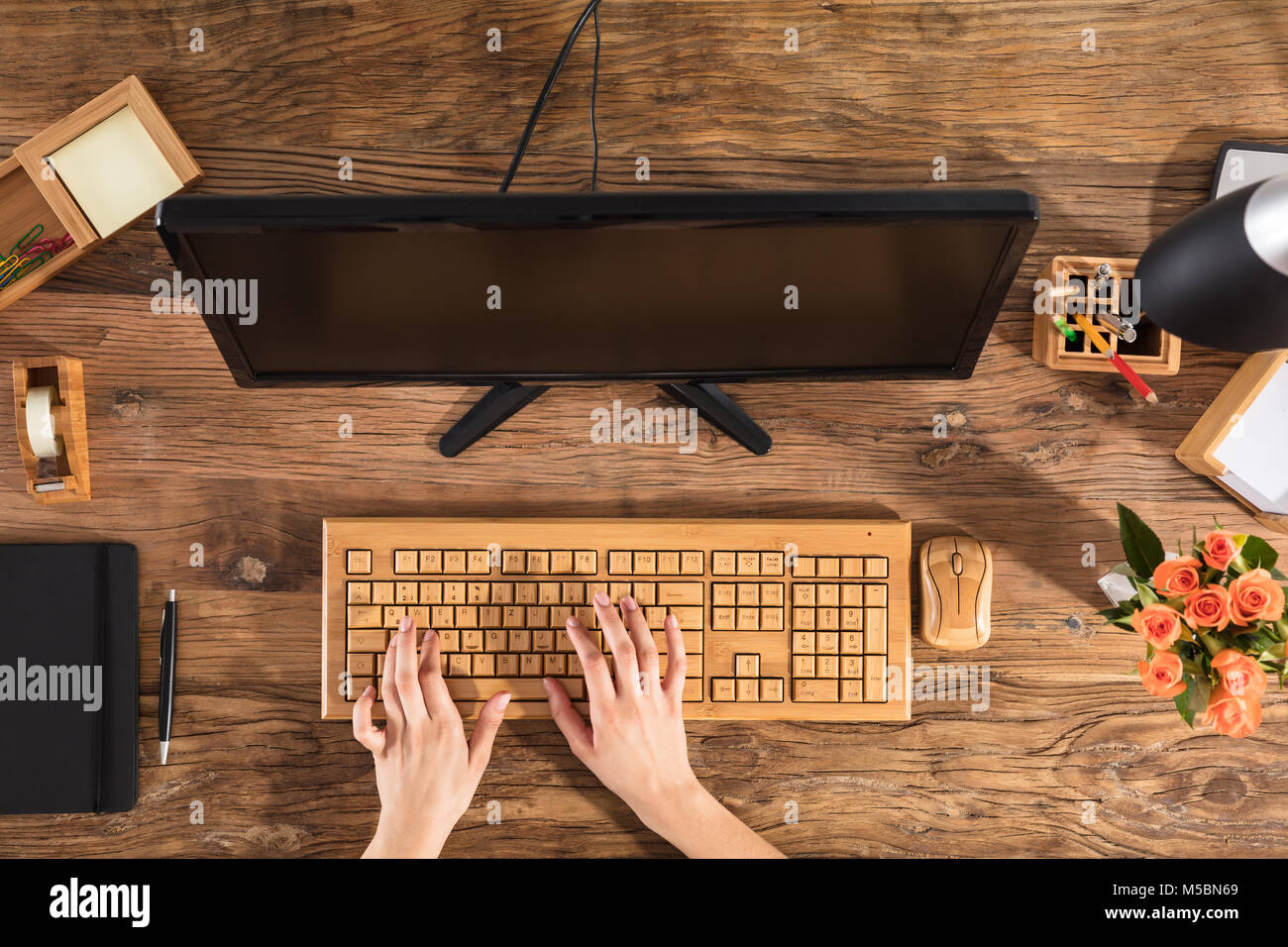 Portrait d'une femme à l'aide du clavier en bois en face de l'ordinateur sur Office 24 Banque D'Images