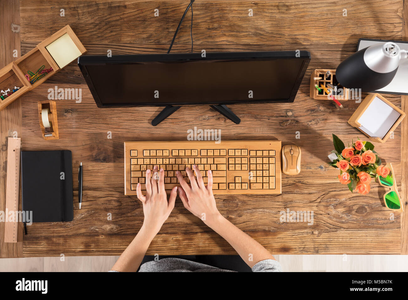 Portrait d'une femme à l'aide du clavier en bois en face de l'ordinateur sur Office 24 Banque D'Images