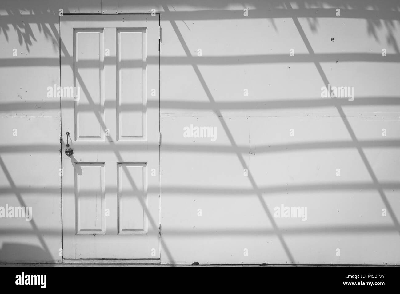 Résumé de droit de vue avant sur porte en bois blanc blanc vieux mur de béton avec l'ombrage de l'ombre sur le mur. Banque D'Images